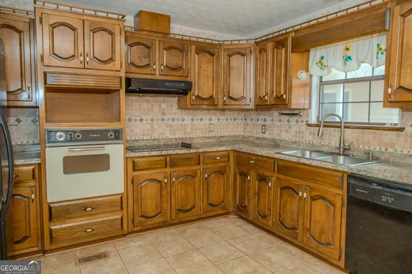 a view of a house with a yard and large trees