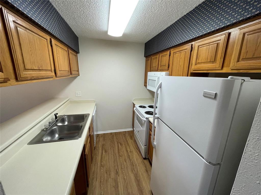 11480 Audelia Road, Unit 231 Dallas, TX 75243 - Photo 8 of 15 a kitchen with a refrigerator a stove and wooden cabinets