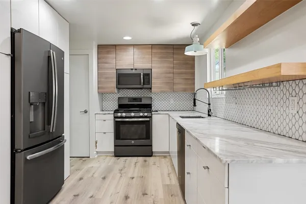 a kitchen with stainless steel appliances granite countertop a sink a stove and a microwave