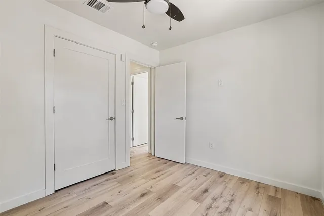 a view of empty room with wooden floor and fan