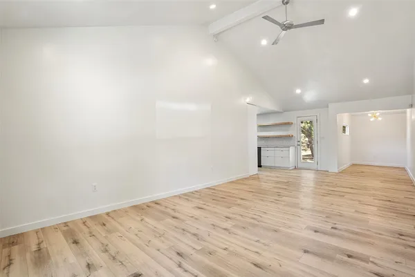 an empty room with wooden floor and a ceiling fan