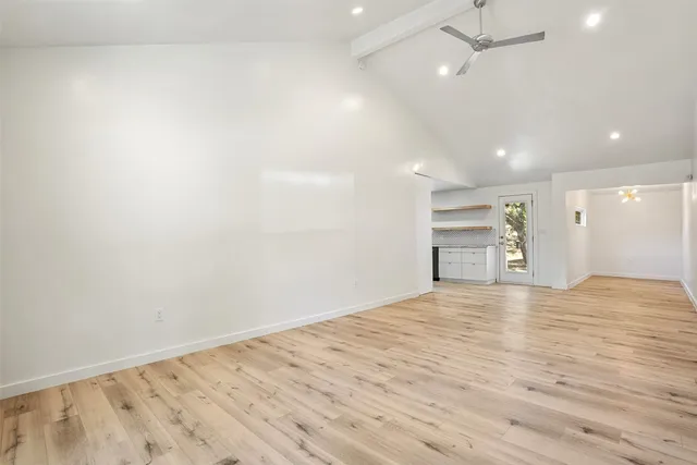 an empty room with wooden floor and a ceiling fan
