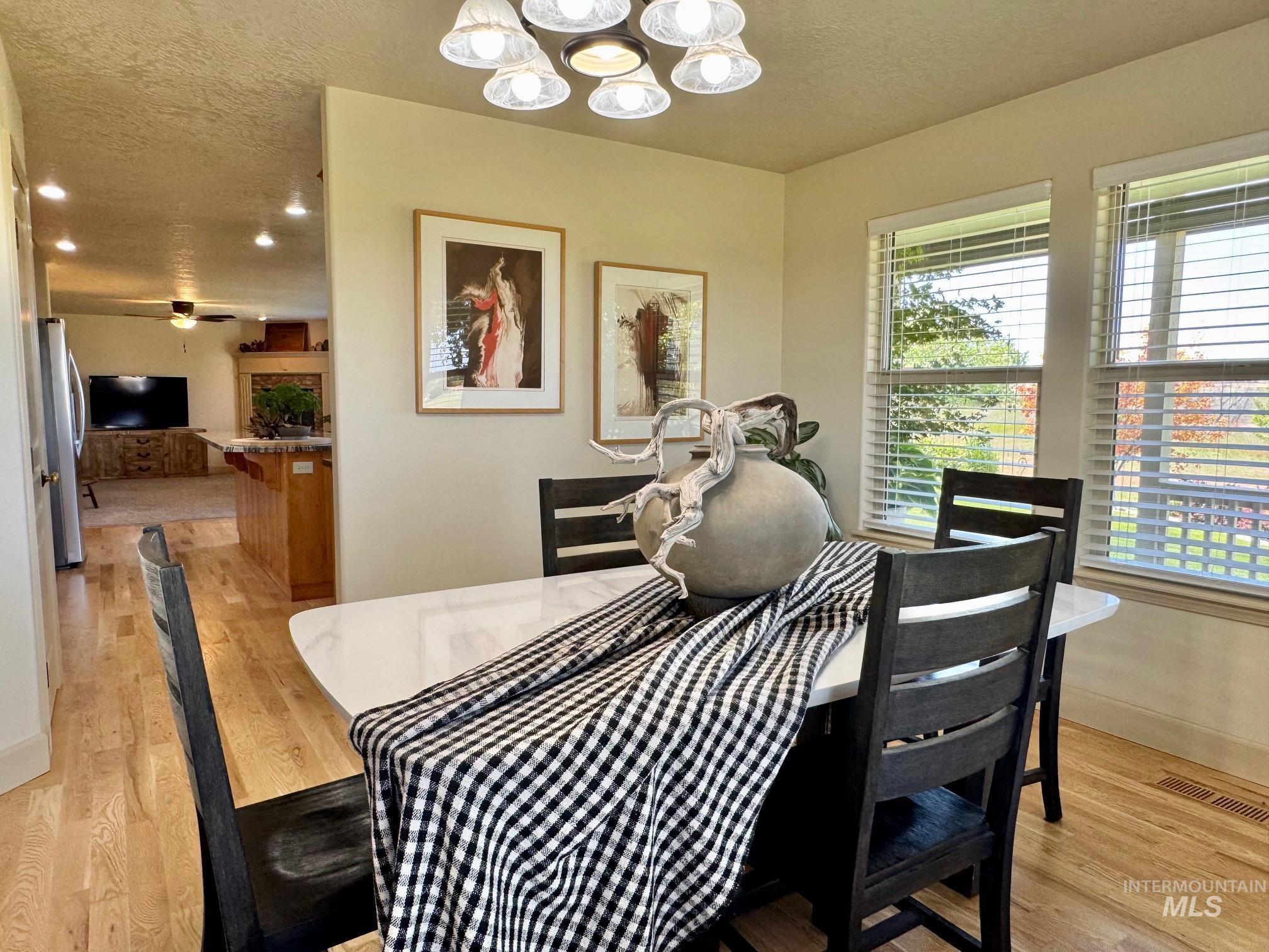 9299 Kemp Road Middleton, ID 83644 - Photo 17 of 50 Dining area featuring wood-finish flooring, a contemporary chandelier, and large windows with horizontal blinds