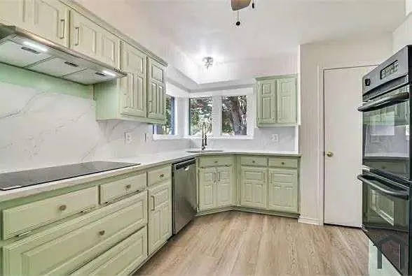a kitchen with granite countertop a sink cabinets stainless steel appliances and a window