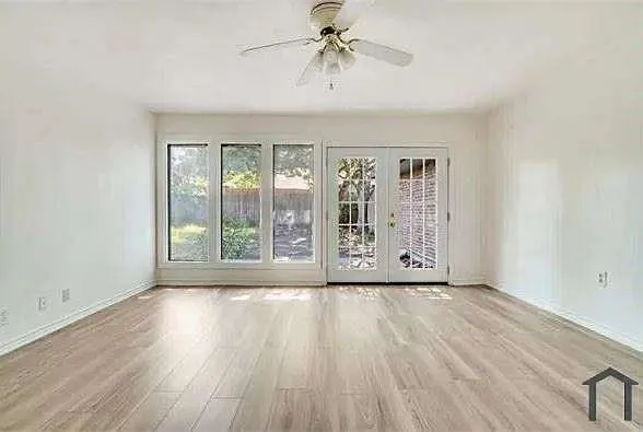 a view of an empty room with a window and wooden floor