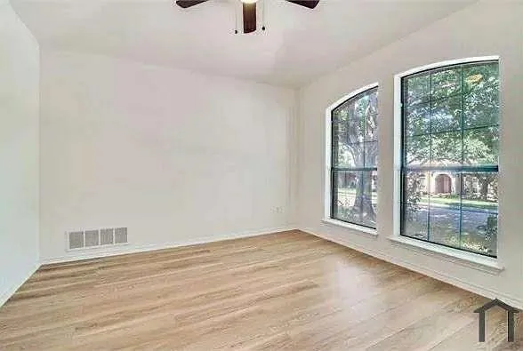 a view of an empty room with wooden floor and a window
