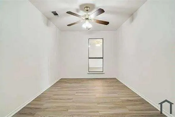 a view of an empty room with window and wooden floor