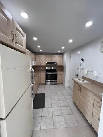 a large white kitchen with stainless steel appliances granite countertop a refrigerator and a stove top oven