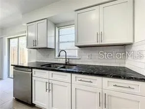 a kitchen with granite countertop white cabinets and sink