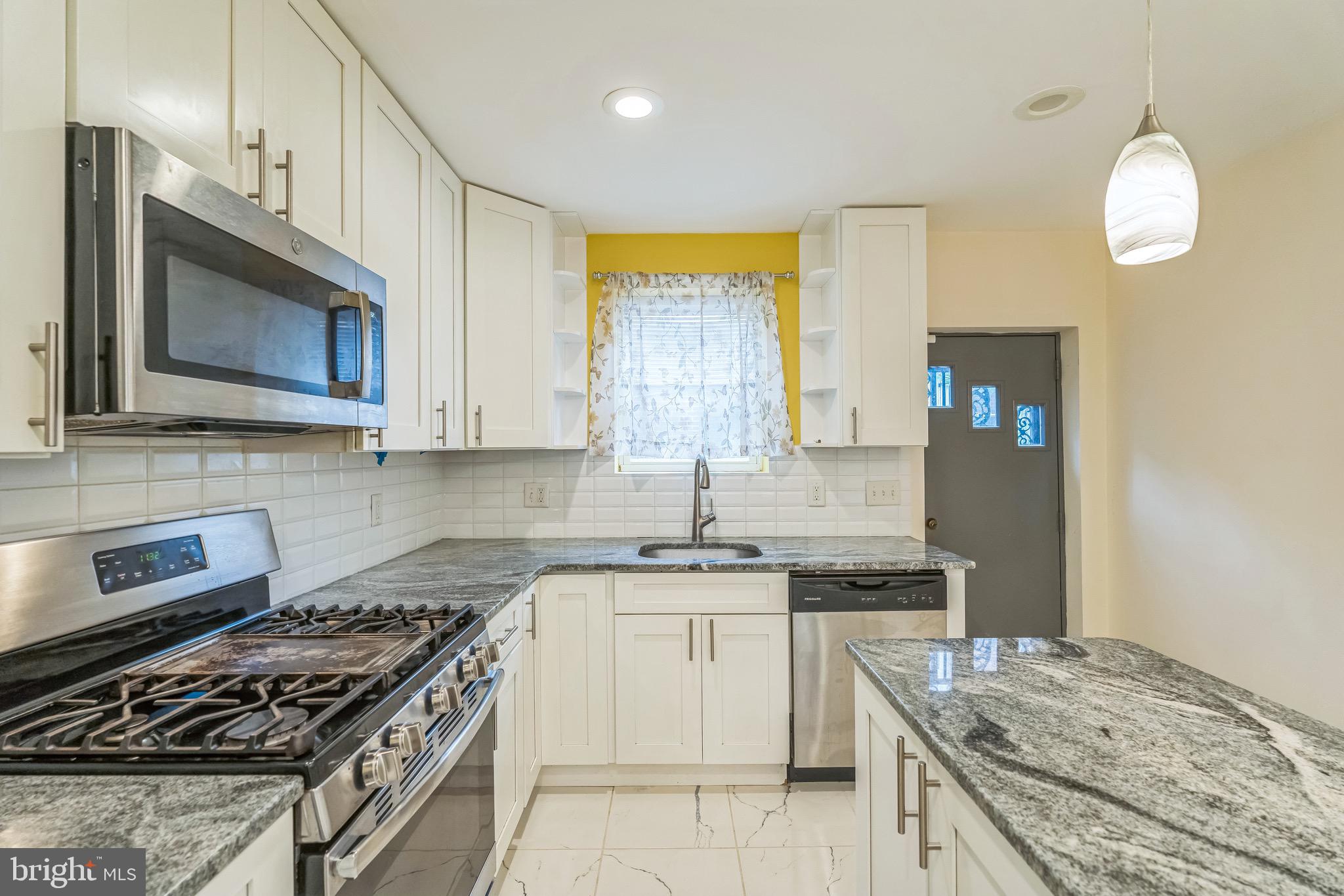 2233 Moore Street Philadelphia, PA 19145 - Photo 10 of 24 a kitchen with stainless steel appliances granite countertop a stove a sink and a microwave