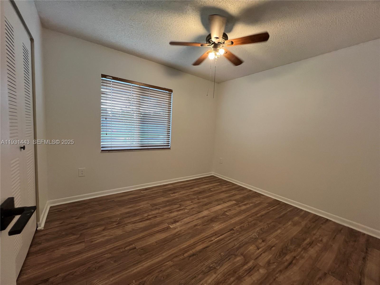 13721 Newport Manor Davie, FL 33325 - Photo 13 of 16 an empty room with wooden floor chandelier fan and windows