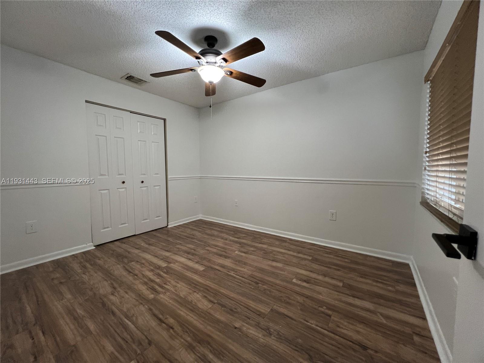 13721 Newport Manor Davie, FL 33325 - Photo 14 of 16 an empty room with wooden floor fan and windows