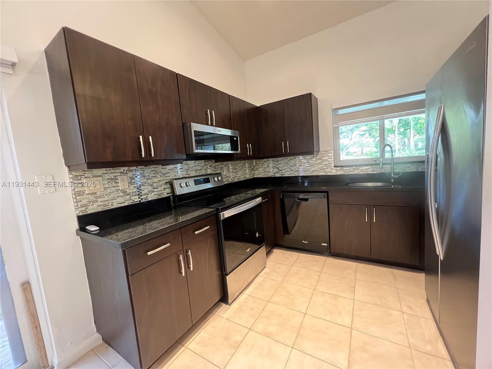 13721 Newport Manor Davie, FL 33325 - Photo 6 of 16 a kitchen with stainless steel appliances granite countertop a stove a sink and a microwave