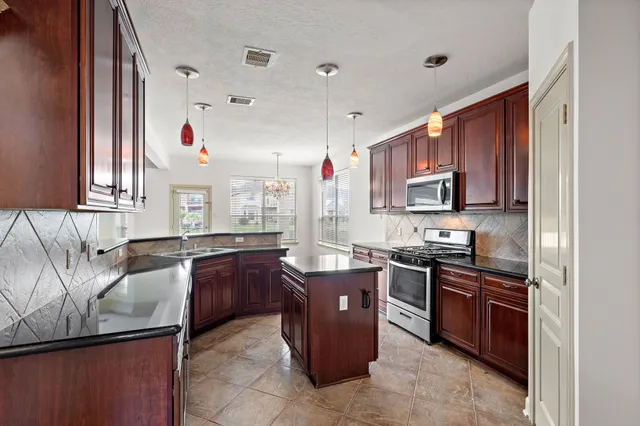 a kitchen with stainless steel appliances granite countertop a sink stove and cabinets