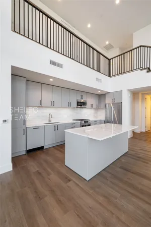 a large white kitchen with kitchen island a sink wooden floor and a refrigerator