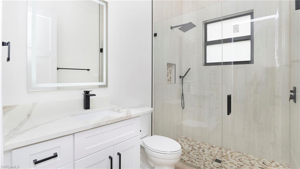 652 15th Street Southwest Naples, FL 34117 - Photo 18 of 47 a bathroom with a granite countertop sink toilet a mirror and shower