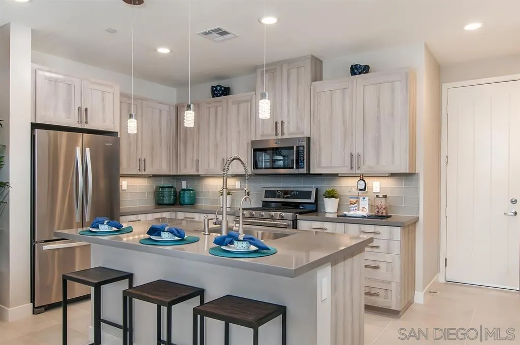 1189 Via Candelas Oceanside, CA 92056 - Photo 6 of 21 a kitchen with stainless steel appliances granite countertop a stove top oven a refrigerator a sink and a refrigerator with wooden floor