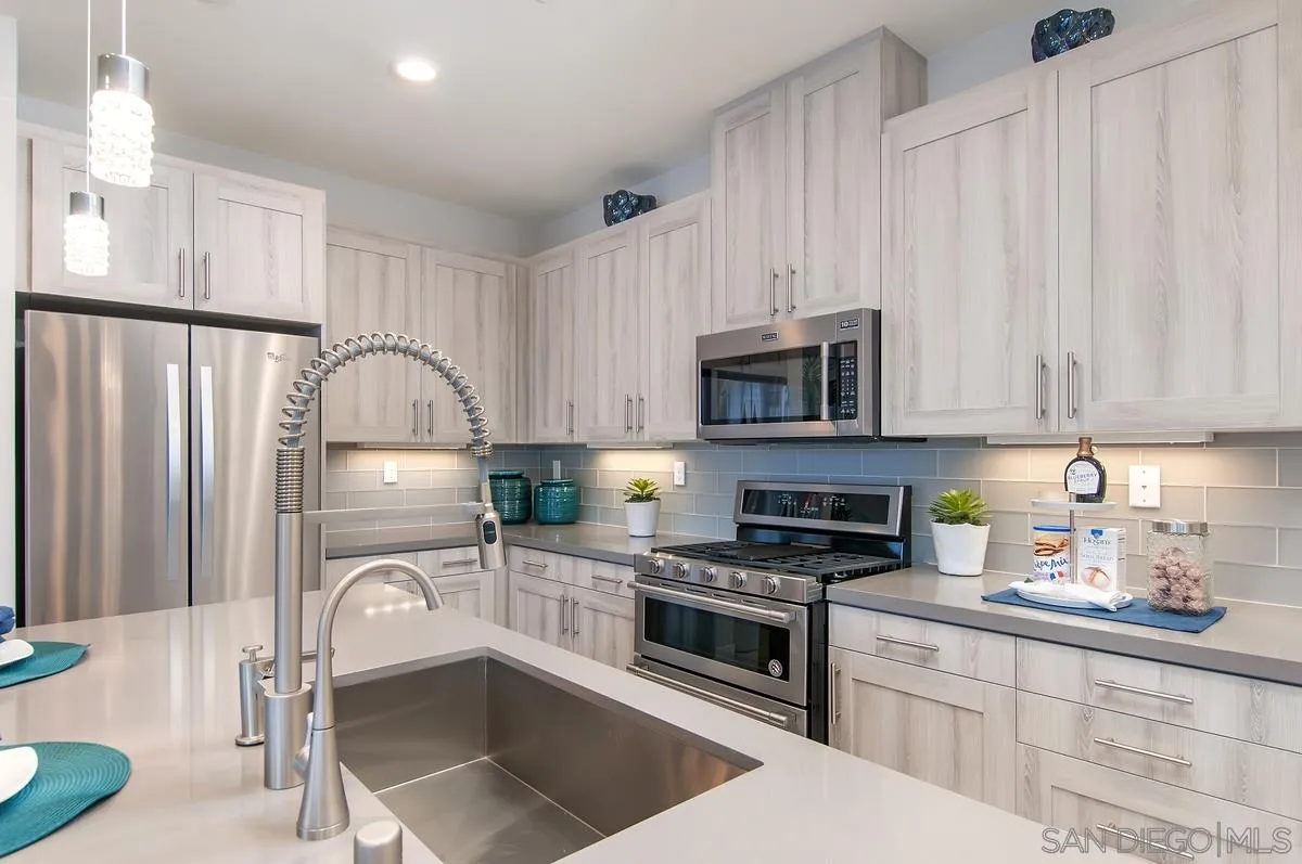 1189 Via Candelas Oceanside, CA 92056 - Photo 9 of 21 a kitchen with granite countertop a stove a sink and a microwave