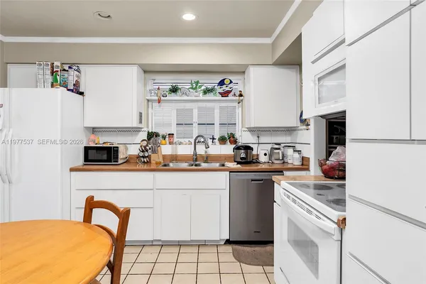 a kitchen with a sink a stove and white cabinets