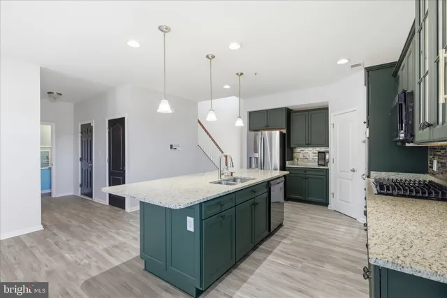 a large kitchen with stainless steel appliances kitchen island a large counter top and a wooden floors