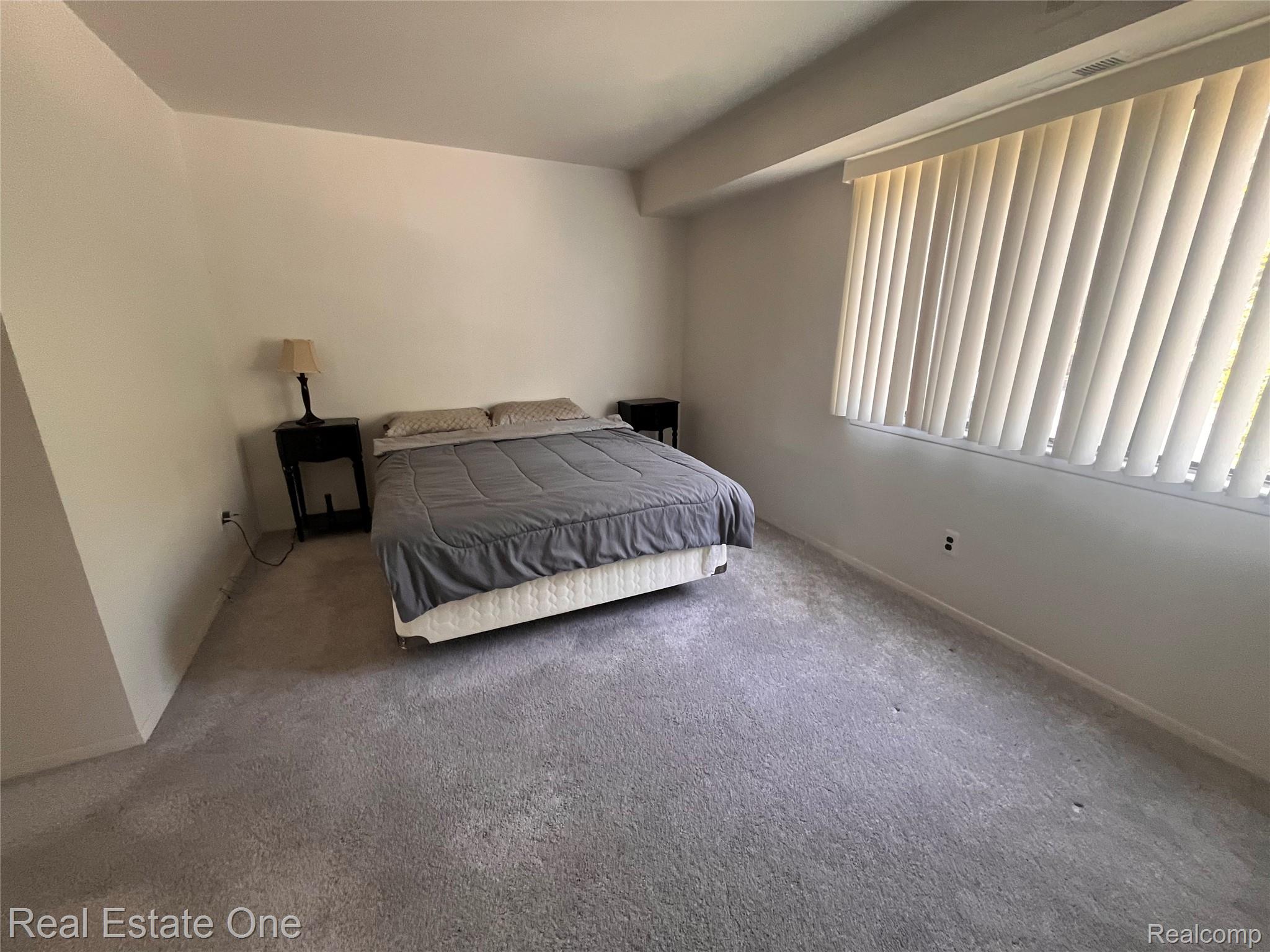 1653 Riverside Drive Rochester, MI 48309 - Photo 11 of 14 Neutral wall paint, window with vertical blinds, and soft gray carpet