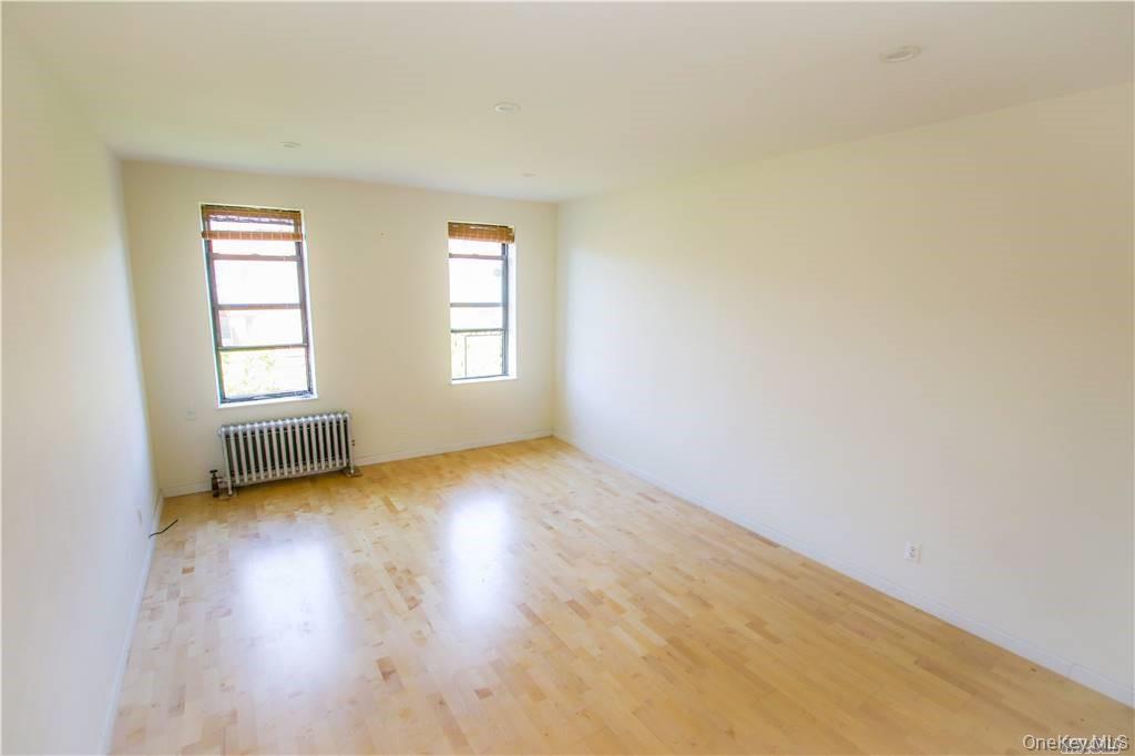 43-33 48th Street, Unit 6D Queens, NY 11104 - Photo 10 of 14 an empty room with wooden floor and windows