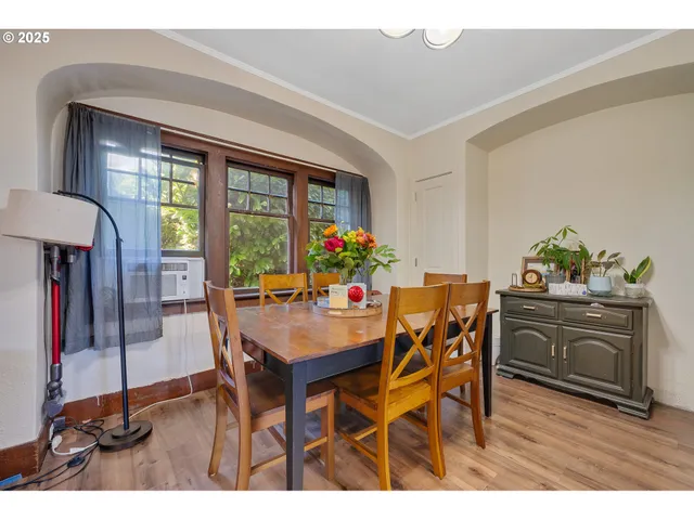 a dining room with furniture a floor to ceiling window and wooden floor