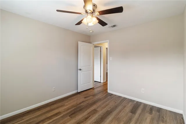an empty room with wooden floor and ceiling fan