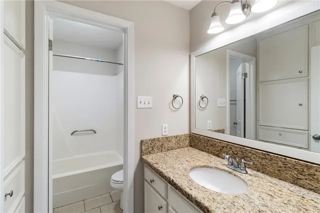 a bathroom with a granite countertop sink a mirror a bathtub and shower