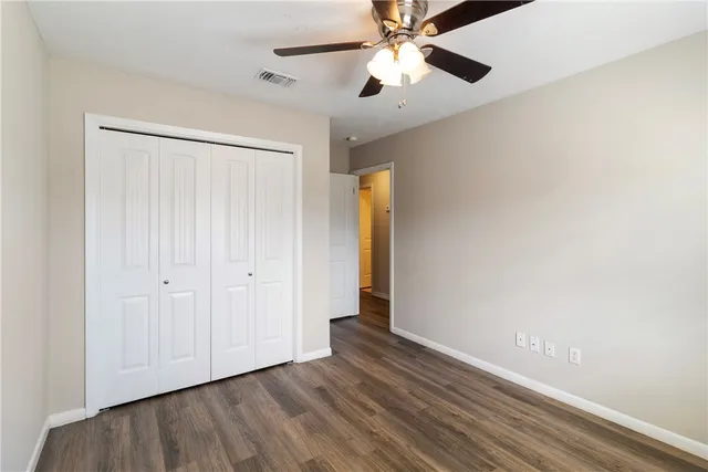 an empty room with wooden floor chandelier fan and closet area