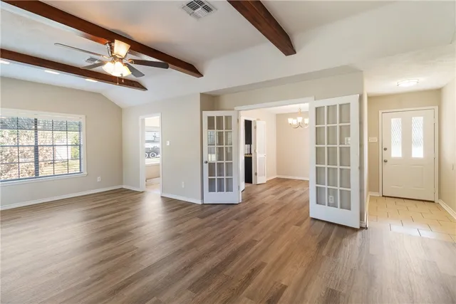 a view of an empty room with wooden floor and a window