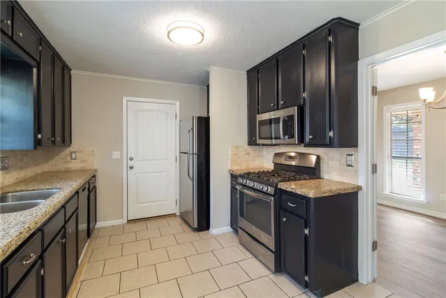 a kitchen with stainless steel appliances granite countertop a stove a sink and a refrigerator