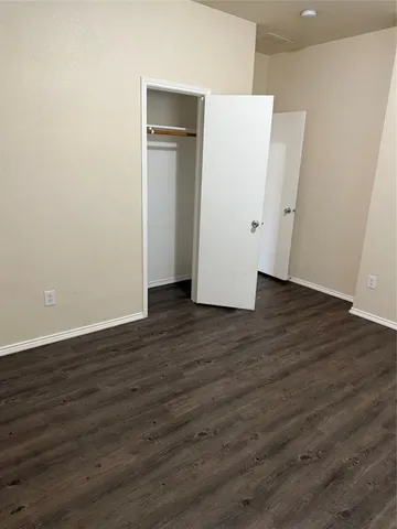a view of an empty room with wooden floor and closet