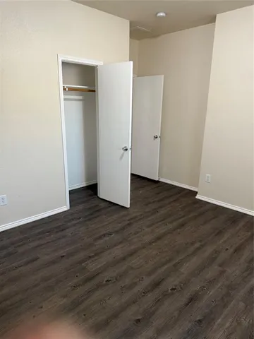 an empty room with wooden floor & closet and windows
