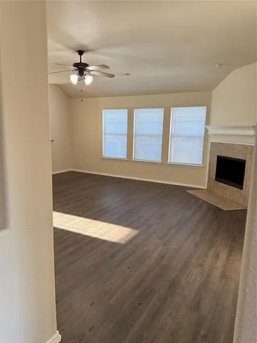 an empty room with wooden floor fan and windows