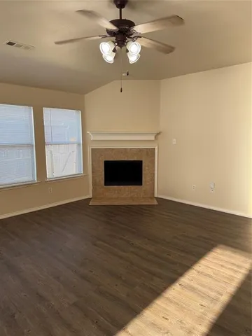 a view of an empty room with wooden floor fireplace and a window