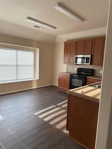 a kitchen with a stove a microwave and a window