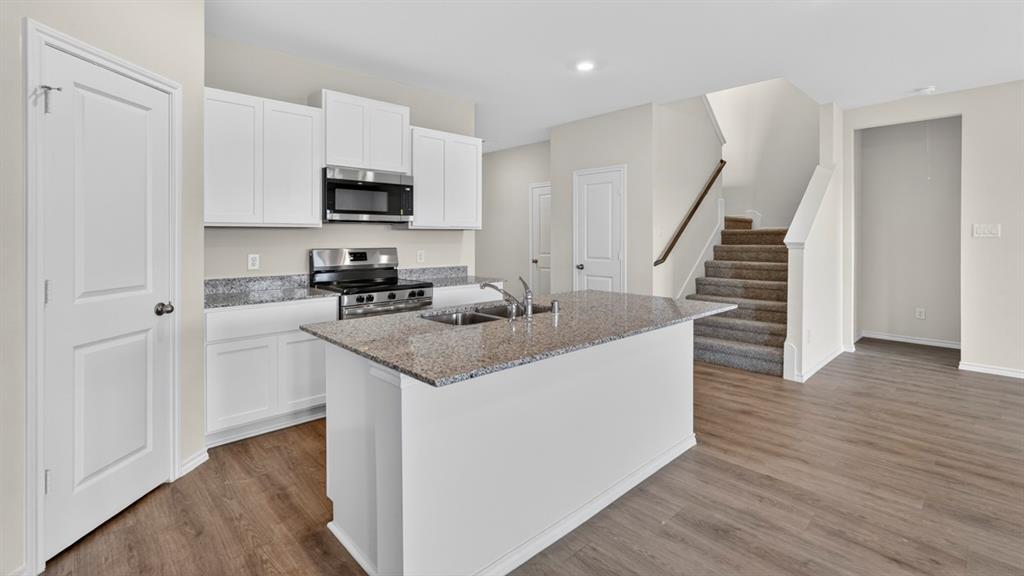1683 Mantle Road Crandall, TX 75114 - Photo 4 of 31 Kitchen island featuring a double-basin sink, granite countertop, and white cabinetry