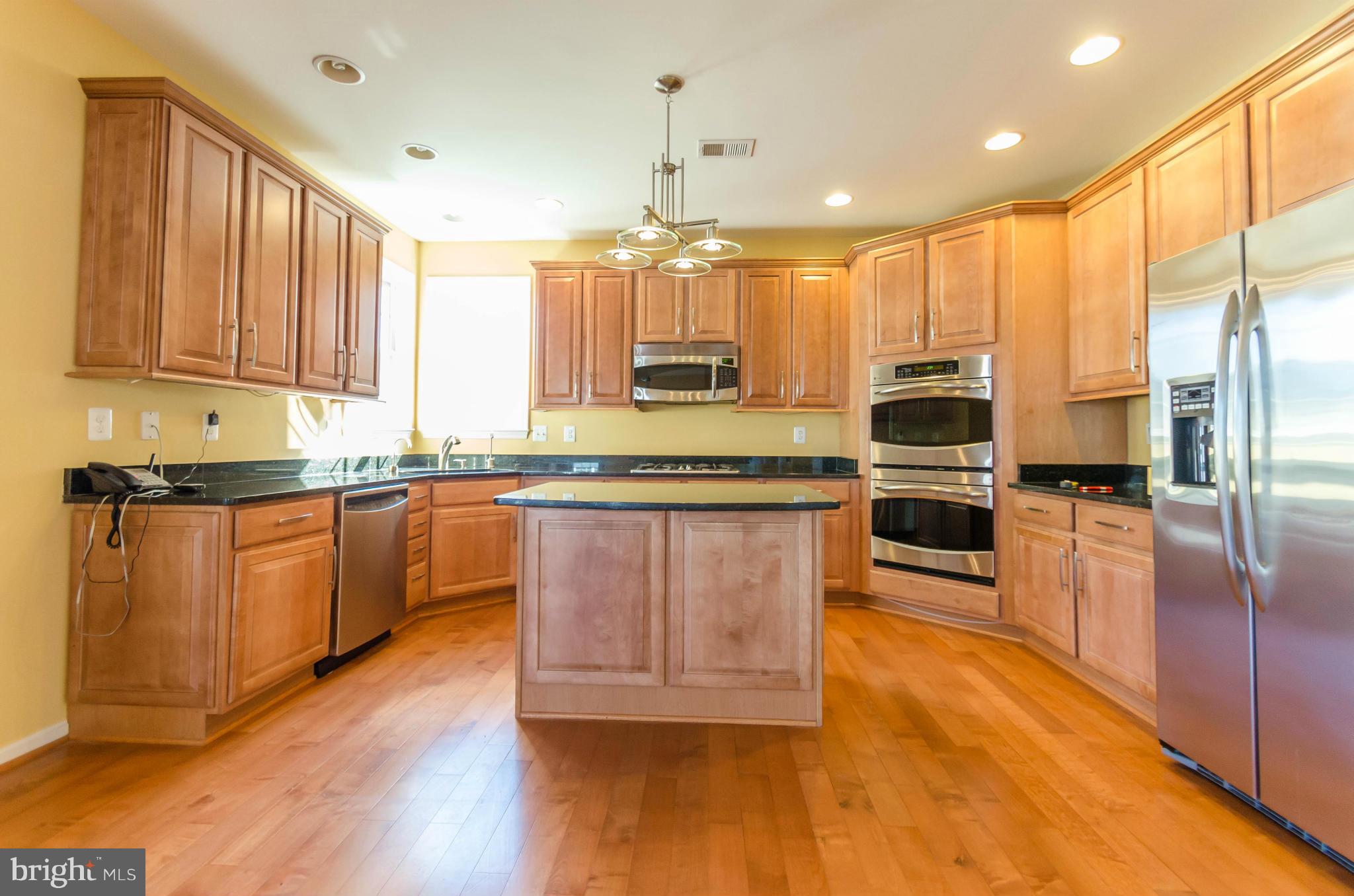 6517 Clarington Road Baltimore, MD 21209 - Photo 11 of 30 a kitchen with stainless steel appliances granite countertop a stove a sink dishwasher a microwave oven and a refrigerator with wooden floor