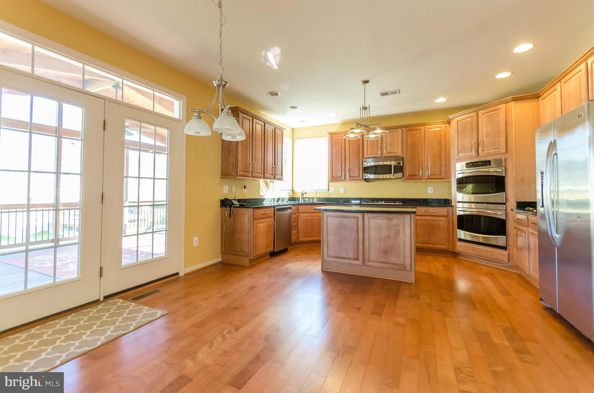6517 Clarington Road Baltimore, MD 21209 - Photo 10 of 30 a kitchen with stainless steel appliances granite countertop a stove top oven a sink dishwasher a refrigerator and white cabinets with wooden floor