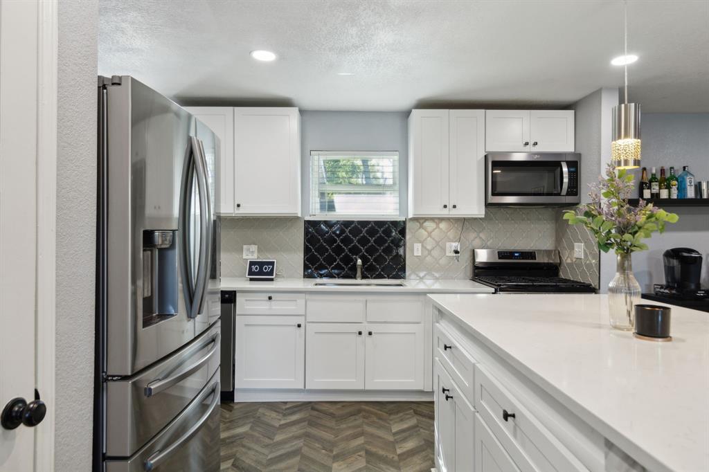 2630 Springvale Drive Farmers Branch, TX 75234 - Photo 8 of 25 a kitchen with white cabinets and stainless steel appliances