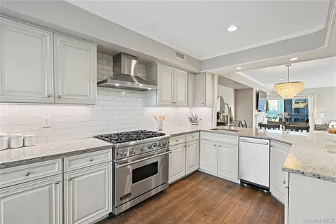 a kitchen with granite countertop stainless steel appliances white cabinets and a wooden floor
