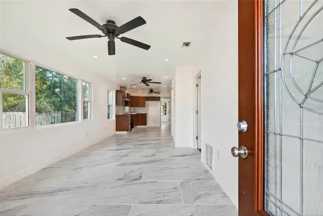 a view of a livingroom with a ceiling fan & a window