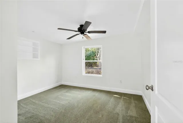 an empty room with a window and a ceiling fan