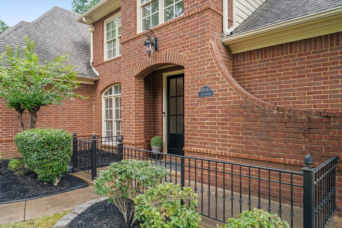 1876 Liles Lane Collierville, TN 38017 - Photo 27 of 36 Brick facade featuring an arched entryway, decorative black railing, and complementary landscaping