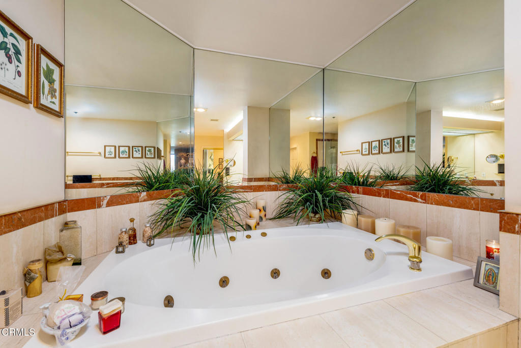 10724 Wilshire Boulevard, Unit 607 Los Angeles, CA 90024 - Photo 25 of 33 a bathroom with a tub a potted plant and a large mirror on the wall