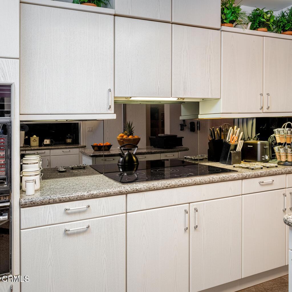 10724 Wilshire Boulevard, Unit 607 Los Angeles, CA 90024 - Photo 6 of 33 a kitchen with granite countertop white cabinets and white appliances