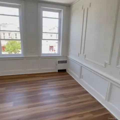a view of empty room with window and wooden floor