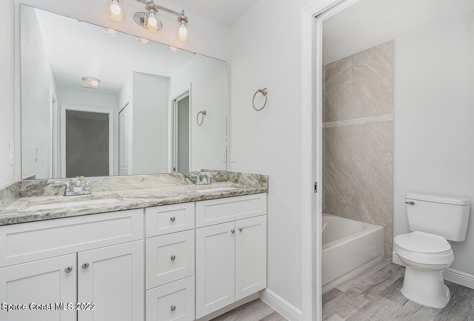 4035 Grant Line Road Mims, FL 32754 - Photo 17 of 18 a bathroom with a granite countertop sink a toilet and a bathtub