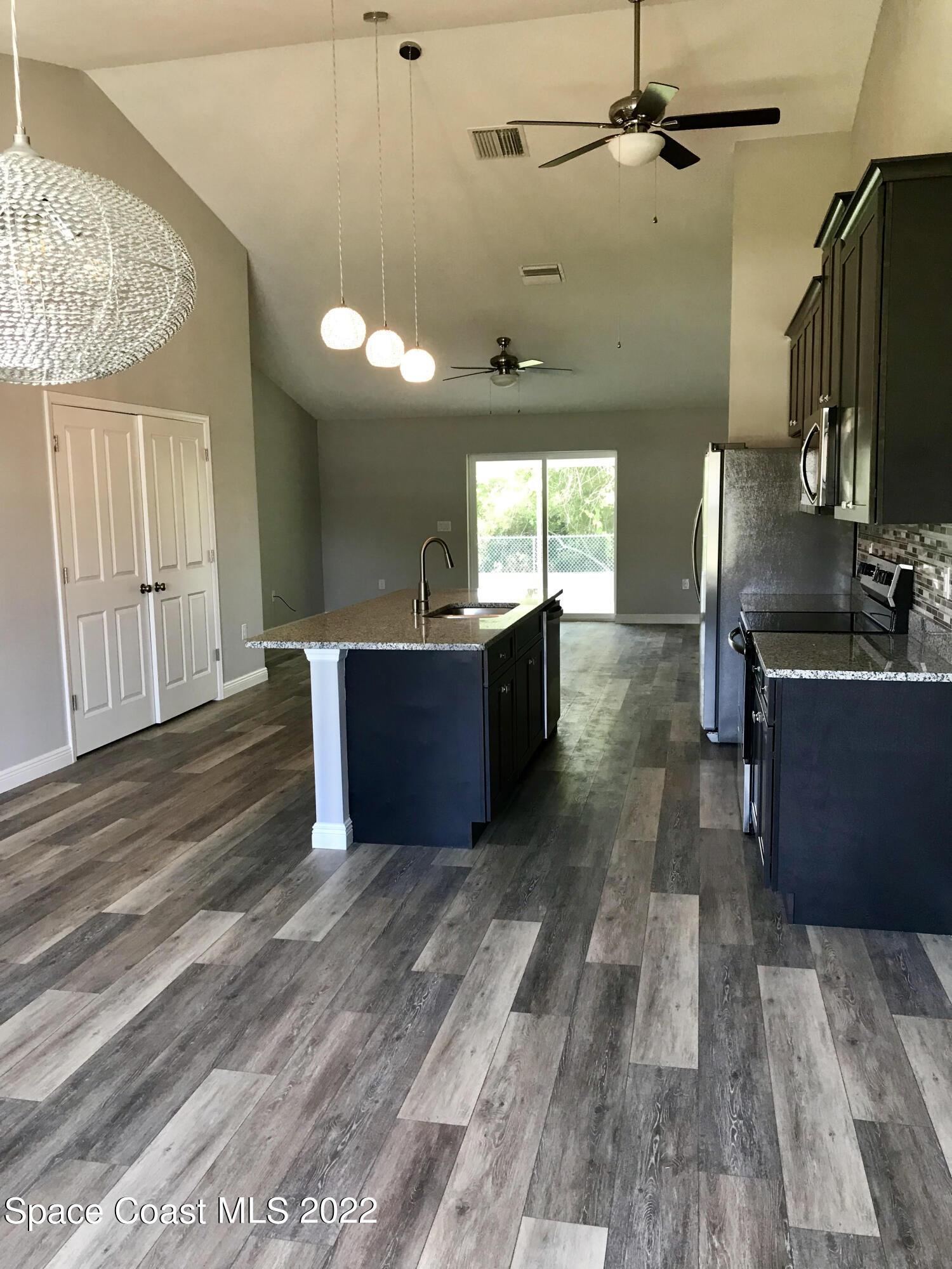 4035 Grant Line Road Mims, FL 32754 - Photo 4 of 18 a view of a kitchen with kitchen island wooden floors appliances and a window